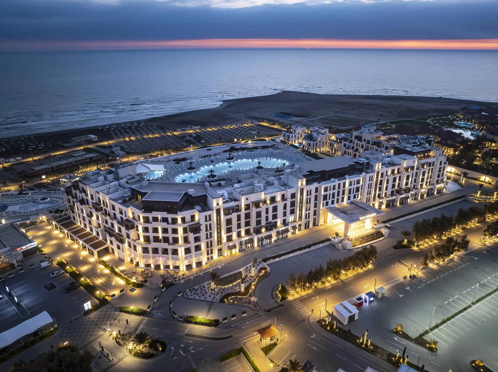 Sea Breeze Baku hotel complex illuminated in the evening, aerial view